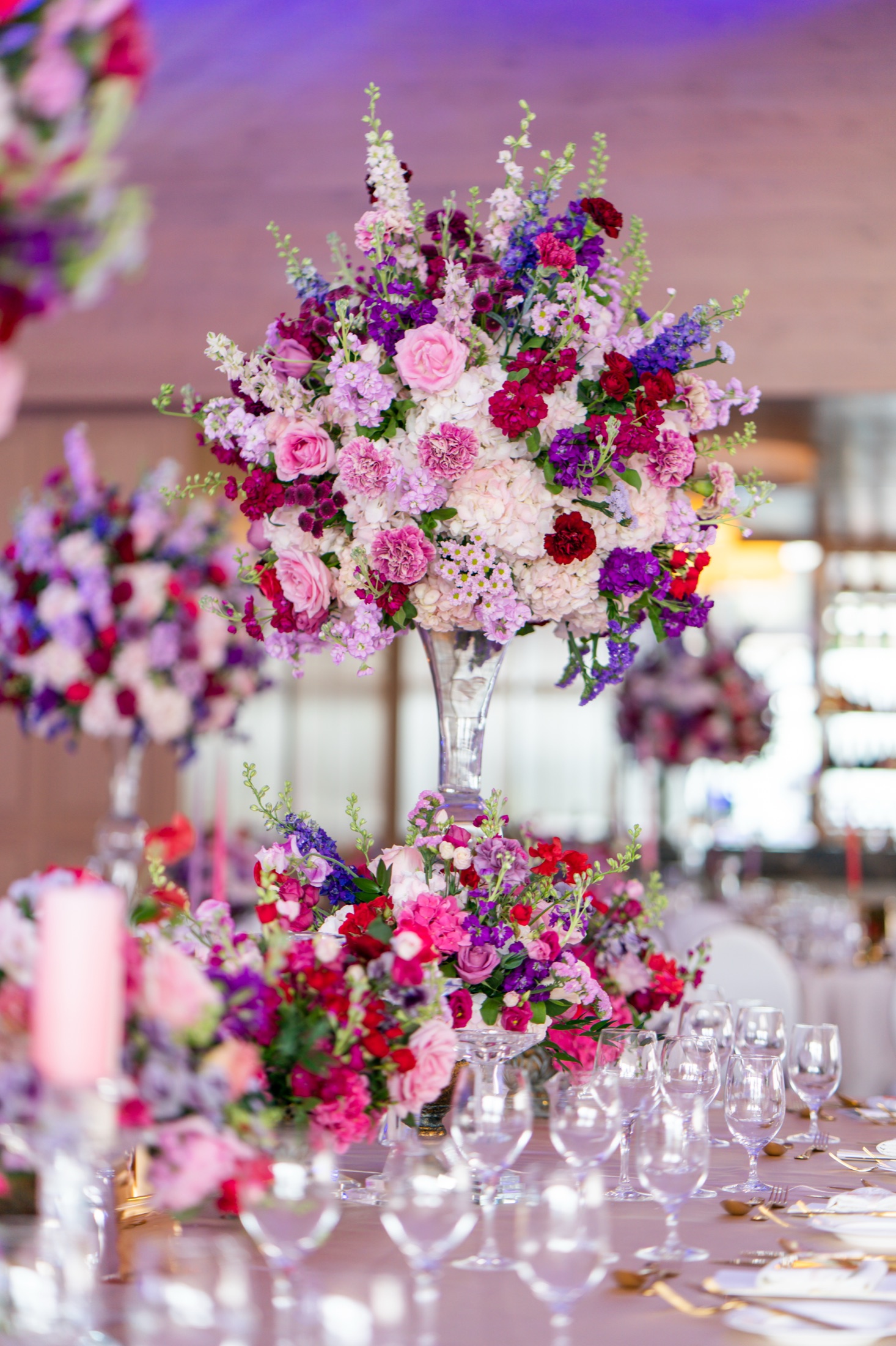 Tall pink and purple floral centrepiece on a wedding table