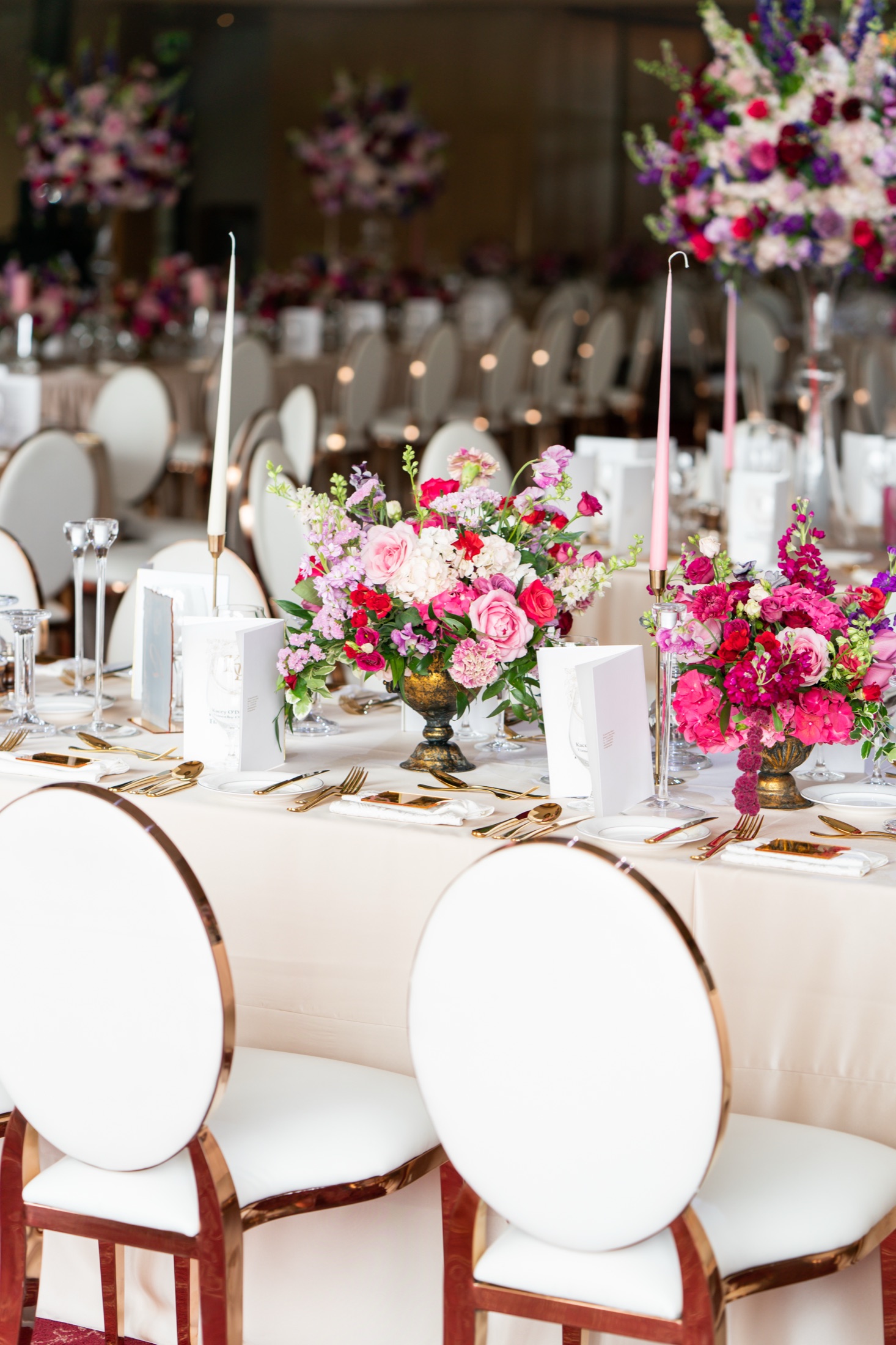 Reception tables styled with pink florals and gold-rimmed chairs